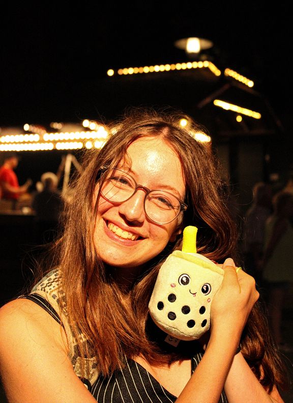 Eine Person auf einem Jahrmarkt, die mit dem gewonnenen Plüschtier post