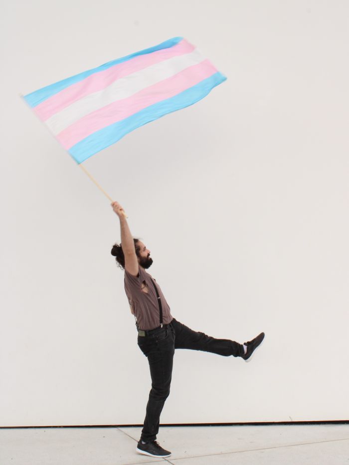 eine Person, die eine Transflagge schwenkt, weißer Hintergrund