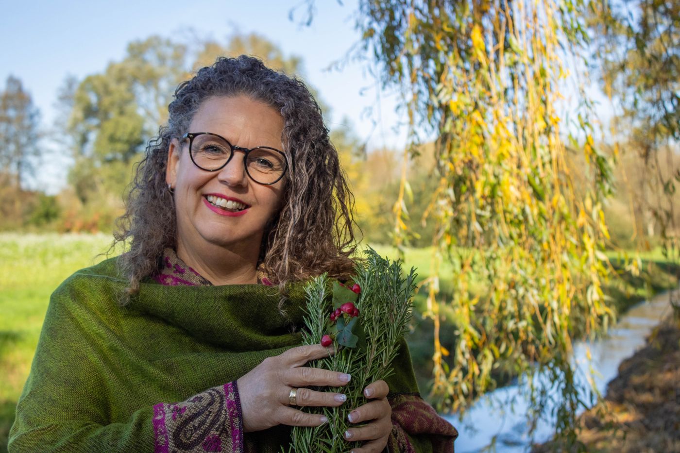 Eine Frau mit einem Kräuterbündel und Natur im Hintergrund